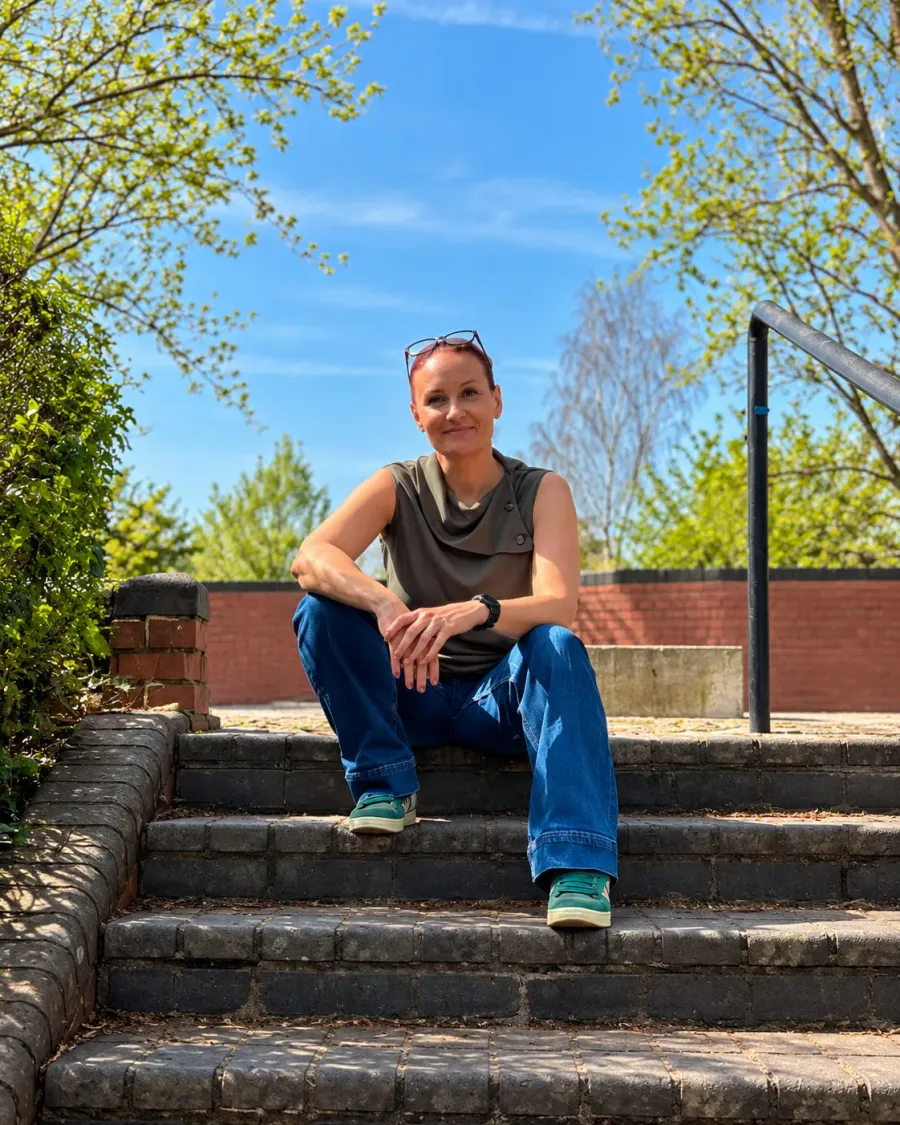 Kelli Doorne-Millott, founder of Neesh, sitting on steps outdoors.